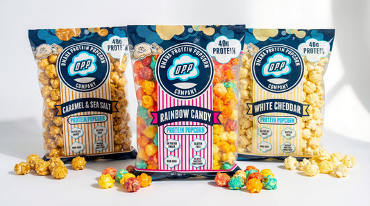 hero image of omaha protein popcorn bags with scattered popcorn and clean bright background